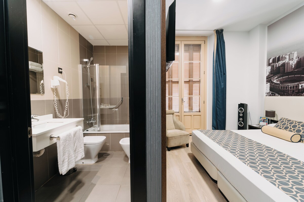 Une chambre à coucher moderne avec un lit, une table de chevet, une lampe et un téléviseur fixé au mur.