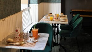 Een eetruimte met een tafel gedekt voor het ontbijt, inclusief een koffiekop, sinaasappelsap en gebak.