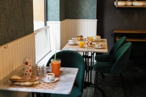 Ein Essbereich mit einem für das Frühstück gedeckten Tisch, einschließlich einer Kaffeetasse, Orangensaft und Gebäck.