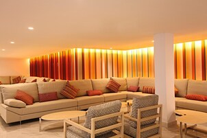 Una sala de estar moderna con un sofá color beige, sillones estampados y una mesa de centro.