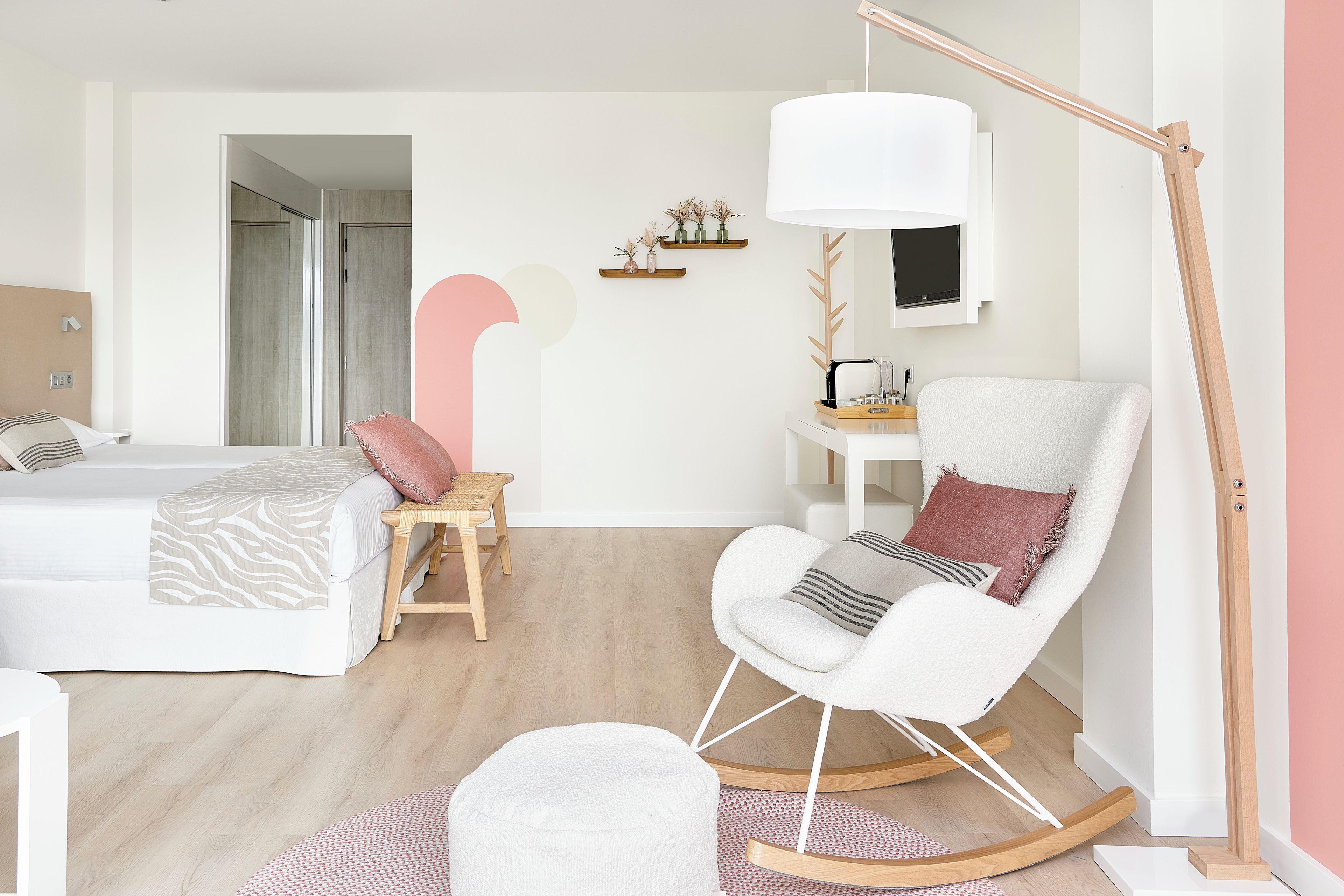 A modern bedroom with a bed, a rocking chair, a desk, and a large floor lamp.