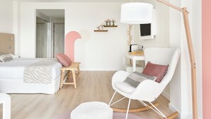 A modern bedroom with a bed, a rocking chair, a desk, and a large floor lamp. - Iberostar Waves Cala Millor (Sant Llorenc des Cardassar)