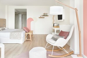 Une chambre à coucher moderne avec un lit, un fauteuil à bascule, un bureau et une grande lampe sur pied.