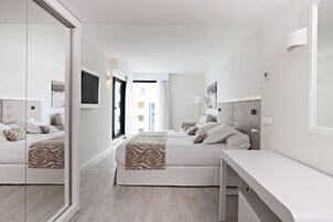 Una habitación de hotel moderna con dos camas, un espejo grande y un escritorio.