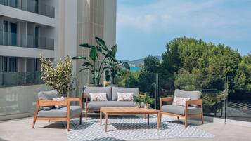 An outdoor seating area with a sofa and two chairs, a coffee table, and potted plants.
