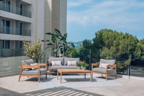 An outdoor seating area with a sofa and two chairs, a coffee table, and potted plants. - Iberostar Waves Cala Millor (Sant Llorenc des Cardassar)