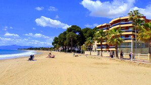 A beach with a building featuring balconies and palm trees. - Rentalmar Sol de España (Cambrils)