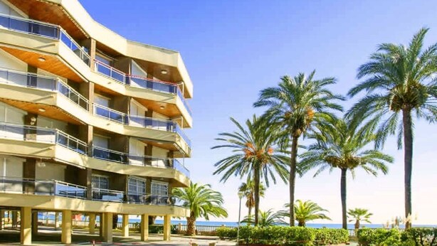 A multi-story hotel with balconies, palm trees, and a view of the sea. - Rentalmar Sol de España (Cambrils)