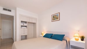 A bedroom with a bed, two bedside tables with lamps, a nightstand, a potted plant, and a wardrobe. - Rentalmar Sol de España (Cambrils)