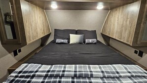 Une chambre à coucher comprenant un lit, deux tables de chevet, un miroir et des armoires encastrées en bois.