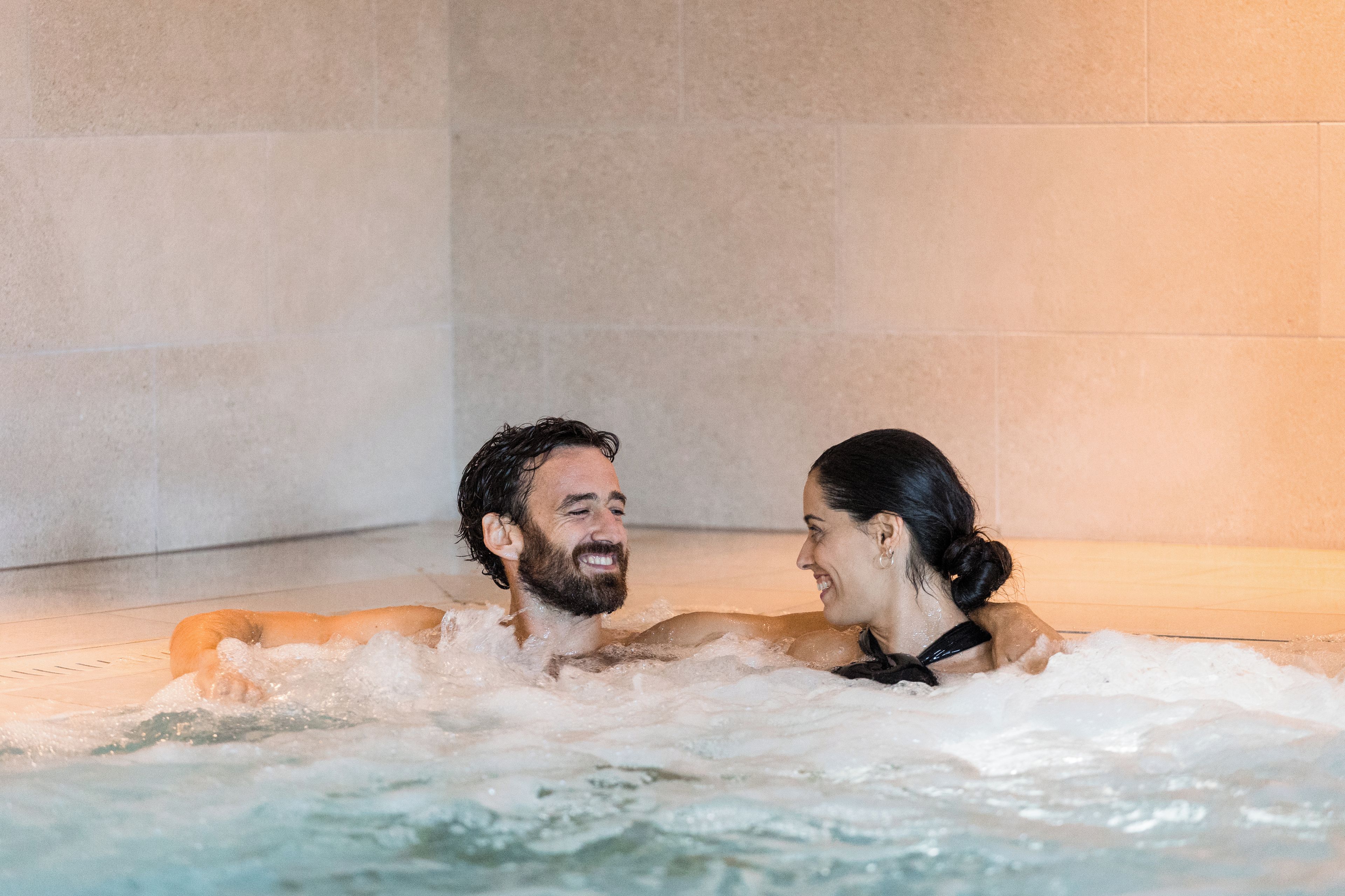Two people in a hot tub with water jets.