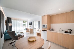 Habitació d'hotel moderna amb zona de dinar, cuineta i vista a l'exterior.