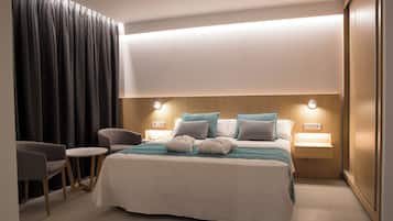 Habitació d'hotel amb un llit gran, dues taules de nit amb làmpades, una cadira i un escriptori.