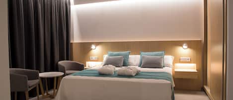 Habitación de hotel con una cama grande, dos mesitas de noche con lámparas, una silla y un escritorio.
