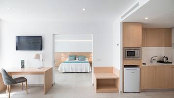 Una habitación de hotel moderna con cama, escritorio, silla y kitchenette.
