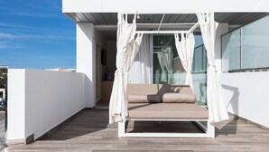 Un espacio exterior moderno con una banca acolchada y un dosel.