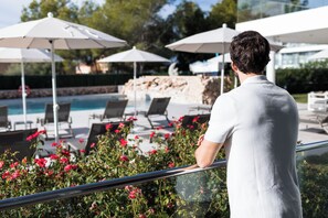 A man standing by a poolside with lounge chairs and umbrellas. - Petit Sagitario (Ciutadella de Menorca)