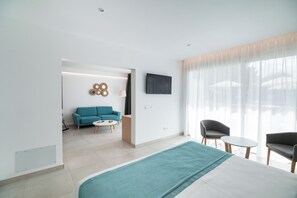 Una habitación de hotel moderna con una cama grande, un televisor montado en la pared, un sofá y una mesita.
