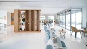 Un moderno vestíbulo de hotel con mostrador de recepción, zona de estar y grandes ventanales con vistas al exterior.
