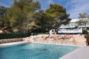 A swimming pool with a stone wall and a boat sculpture.