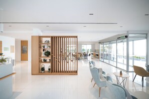 Un área de recepción moderna con un separador de madera, asientos y vistas al exterior.
