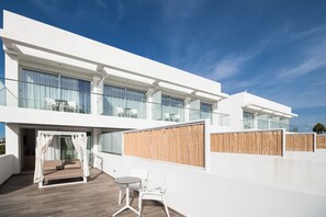 Un edificio moderno con balcón, una silla colgante y una pequeña mesa con sillas.