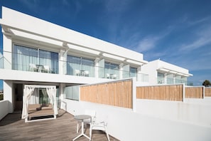 Un edificio moderno con balcón, una silla colgante y una pequeña mesa con sillas.