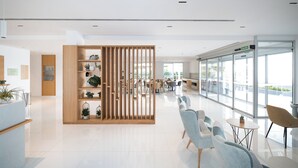 Un área de recepción moderna con un separador de madera, asientos y vistas al exterior.