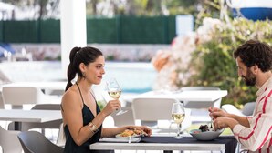 Un comedor con mesas y sillas, una piscina al fondo y vistas al exterior.