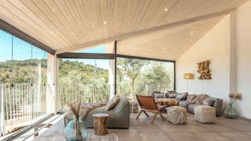 Un amplio salón con un gran ventanal que ofrece vistas al exterior, un diseño de techo moderno y un cómodo conjunto de asientos.