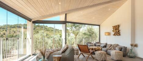 Un amplio salón con un gran ventanal que ofrece vistas al exterior, un diseño de techo moderno y un cómodo conjunto de asientos.