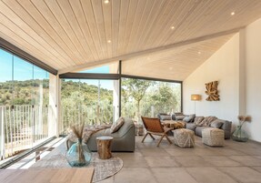 Un amplio salón con un gran ventanal que ofrece vistas al exterior, un diseño de techo moderno y un cómodo conjunto de asientos.