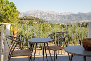 Un balcón con dos sillas y una mesa, con vistas a un paisaje montañoso.