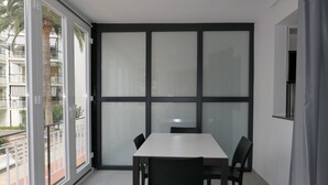 A modern room with a large window, a white table, and black chairs. - Rentalmar Aries Plus (Salou)