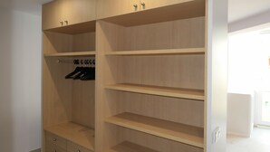 A walk-in closet with wooden shelving and hanging space. - Rentalmar Aries Plus (Salou)