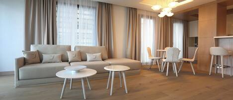 A modern living room with a sofa, two round tables, and a bar area.
