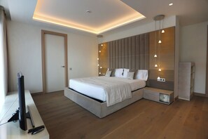 A modern bedroom with a large bed, bedside tables, a TV, and a built-in wardrobe. - Cosmo Apartments Platja D'aro (Castell-Platja d'Aro)