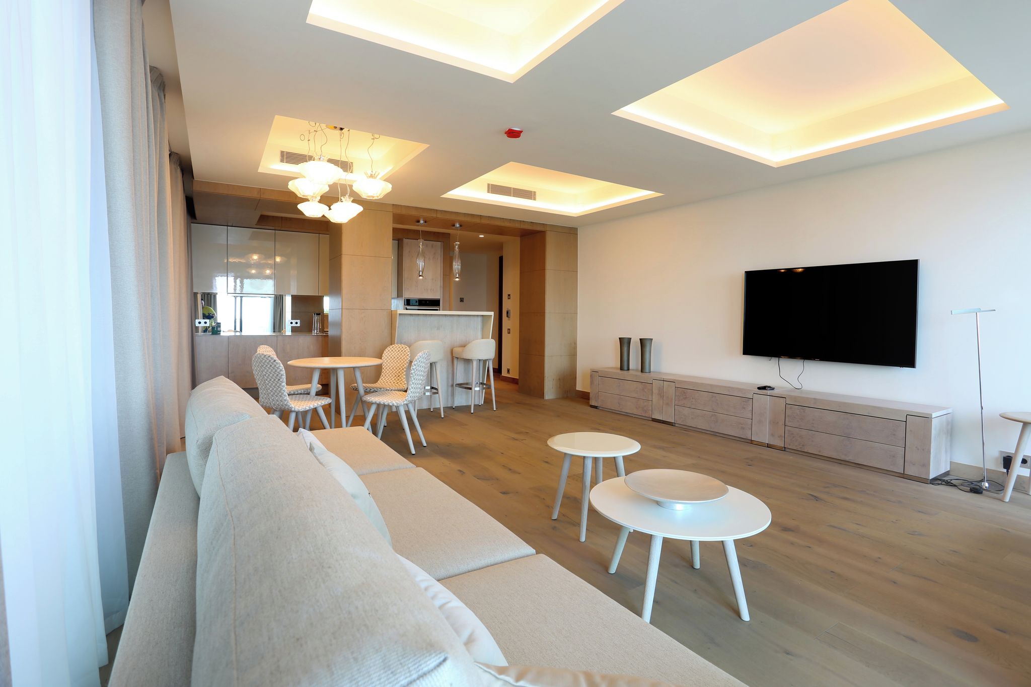 Un salon moderne comprenant un canapé, une table à manger, des chaises, un téléviseur et un coin cuisine.