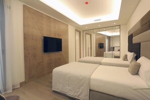 Una habitación de hotel moderna con dos camas, un televisor de pantalla plana montado en la pared y un espejo grande que refleja la habitación.