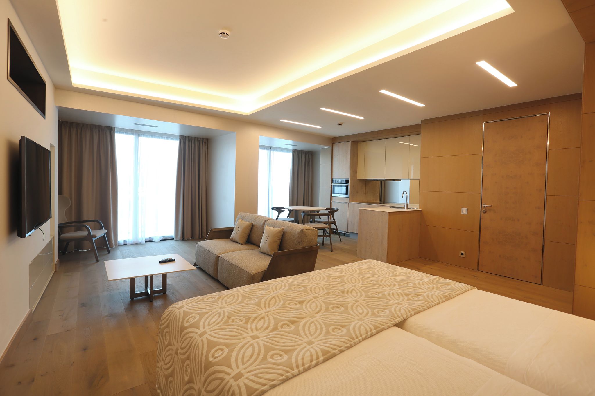 Una habitación de hotel moderna con una cama grande, un sofá, un escritorio y una kitchenette.