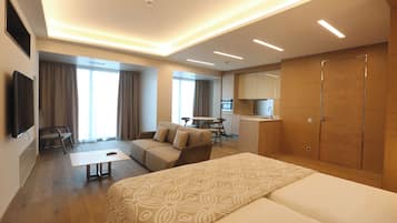 Una habitación de hotel moderna con una cama grande, un sofá, un escritorio y una kitchenette.