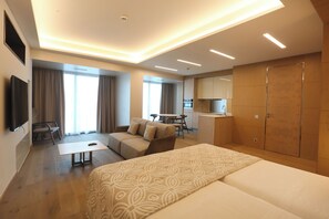 Ein modernes Hotelzimmer mit einem großen Bett, einer Couch, einem Schreibtisch und einer Küchenzeile.