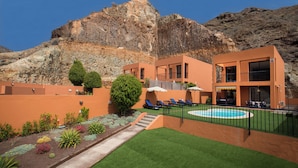 Un hotel con piscina, area relax all'aperto e montagne sullo sfondo.