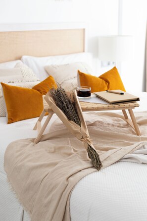 Un letto rifatto con cura, un tavolino in legno, un quaderno, una penna e una tazza di tè.