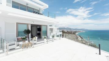 A modern white building with a balcony overlooking a coastal view.