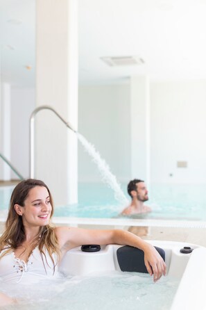 A woman relaxing in a hot tub with a man in the background. - Apartamentos Martalia Nerja (Torrox)