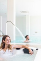 A woman relaxing in a hot tub with a man in the background.