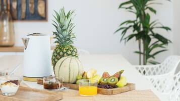 Ein Esstisch mit einer Ananas, Wassermelone und verschiedenen Früchten und Getränken.
