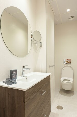 Een moderne badkamer met een grote spiegel, een wit wastafelmeubel en een toilet.