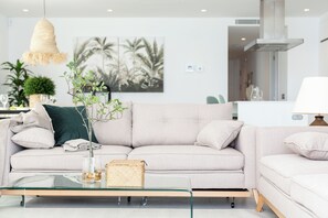 A modern living room with a sofa, a glass coffee table, and a hanging light fixture. - Apartamentos Martalia Nerja (Torrox)